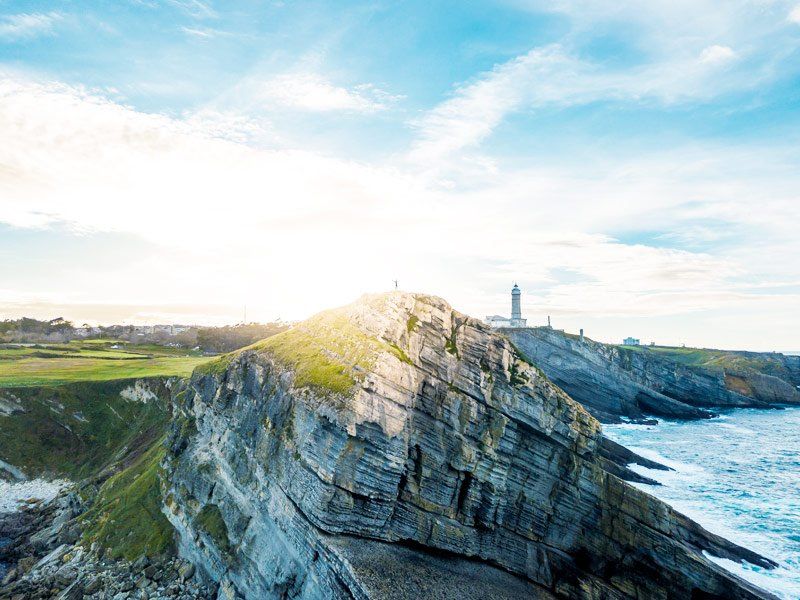 Paisaje de barrancos que dan al mar en Cantabria con un hombre al fondo abriendo los brazos