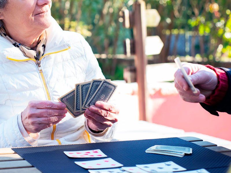 Dos personas mayores jugando a las cartas al aire libre en Residencia Las Cumbres