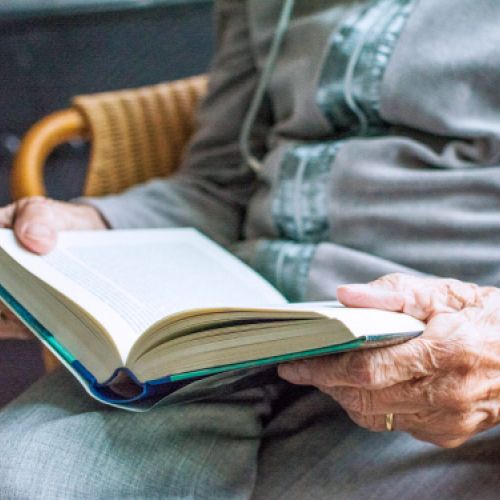 Persona mayor leyendo un libro sentada en Residencia Las Cumbres